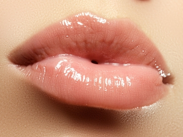 Glossy, pink lips close-up, with visible texture and shine.