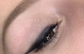 A close-up of a person's closed eye shows a clean, bold black eyeliner wing on the upper eyelid and a well-groomed eyebrow.