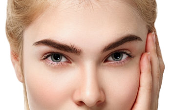 Close-up of a person's face with light skin, blue eyes, and blonde hair, resting their hand on their cheek.