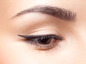 Close-up of a closed eye with winged black eyeliner and groomed eyebrow.