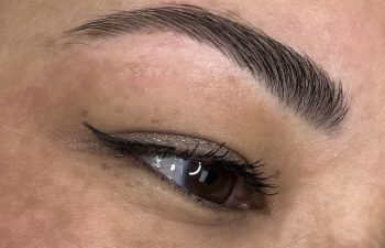 Close-up of an eyebrow and eye with healed eyebrow microblading and eyeliner, shown 2 years after the procedure, before a touch-up.